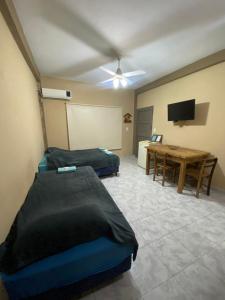 a room with two beds and a table and a tv at LU DORMIS Alquiler Temporario in Corrientes