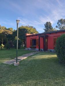 een rood huis met een straatlicht in het gras bij Casa Quinta Pichi Ruca in Coronel Suárez