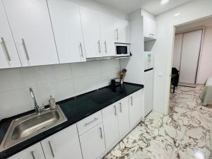 a white kitchen with a sink and a microwave at Aladín House Vinaròs playa in Vinaròs