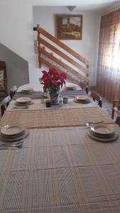 a dining room table with plates and red flowers on it at Gaiamoment La casa la panadera in Alcalá del Júcar