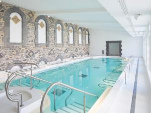 une grande piscine dans un bâtiment avec un mur de briques dans l'établissement Appartement T2 - RDC à 300M des thermes - La villa blanche, à Le Mont-Dore