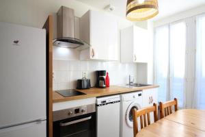 une cuisine avec un réfrigérateur blanc et une table dans l'établissement Appartement T2 - RDC à 300M des thermes - La villa blanche, à Le Mont-Dore