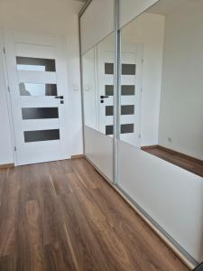 una camera con porte scorrevoli in vetro e pavimento in legno di Apartament Słoneczny Taras przy Aquapark Reda a Rumia