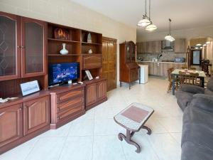 a living room with a couch and a tv at Seashell Stories - Modern Comforts, Traditional Charm in Nadur