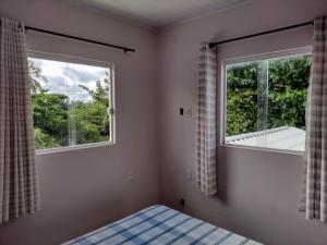 a bedroom with a bed and two windows at Refúgio Guarajuba, 50m da Praia, Piscina, Recarga EV, área gourmet, churrasqueira in Camaçari