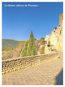 a stone wall next to a road with a tree at La Bonne Adresse - Gite ZENITUDE in Cornillon-Confoux