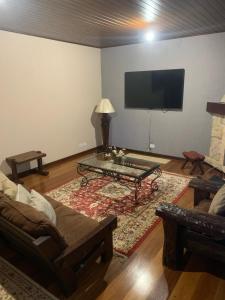 a living room with a couch and a tv on the wall at Casa na serra in Campos do Jordão