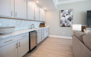 a kitchen with white cabinets and a sink and a couch at Phoenix Gulf Towers 806 condo in Gulf Shores