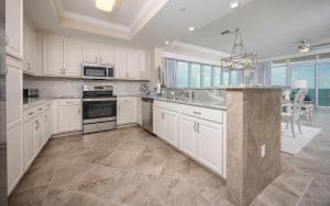 a large kitchen with white cabinets and a large island at Phoenix Gulf Towers 1008 condo in Gulf Shores