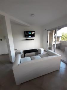 a white living room with a white couch and a tv at Dpto 2 dormir Mitre in Neuquén