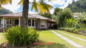 a house with a palm tree in the yard at Chale Rustico com Vista para a Montanha in Venda Nova do Imigrante