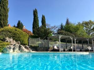 a large swimming pool with chairs and a gazebo at Le Mas de Jouas in Saint-Rémy
