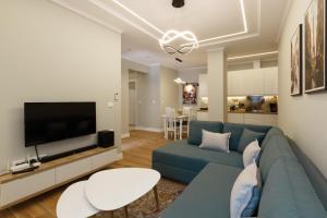 Una sala de estar con un sofá azul y un televisor de pantalla plana. en GjiroCasa Apartament, en Gjirokastra