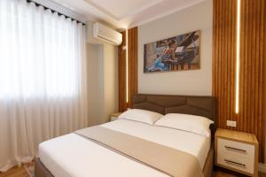 Un dormitorio con una cama blanca y una ventana. en GjiroCasa Apartament, en Gjirokastra
