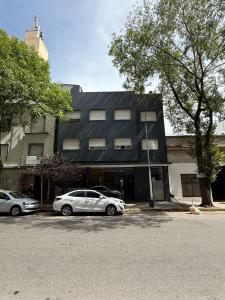 two cars parked in a parking lot in front of a building at Hotel Canciller in Mar del Plata