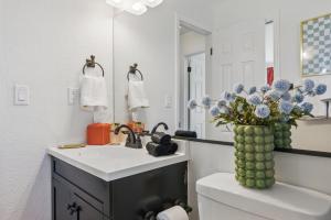 a bathroom with a sink and a vase of flowers on a toilet at Spacious 4BD - Backyard BBQ, Fire Pit & Mini Golf in Arvada +52 photos