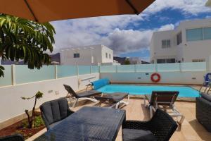Un patio con mesa y sillas y una piscina. en Villa Pousadoiro, en Playa Blanca