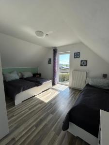a bedroom with two beds and a large window at Boddenhus Loissin in Loissin