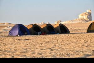 a group of tents sitting in the desert at Camp White Desert in Bawati