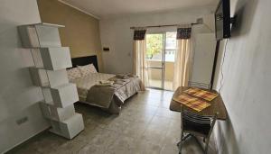 a bedroom with a bed and a table and a desk at Departamento Pellegrini in San Pedro