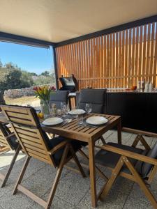 una mesa de madera y sillas en una sala de estar con mesa y sillón en Sunny Stay - Mobile home 1 minute from beach with free parking and wifi!, en Pirovac