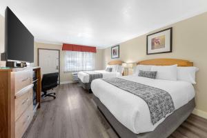 a hotel room with two beds and a flat screen tv at Best Western Plus Ontario Airport & Convention Center in Ontario