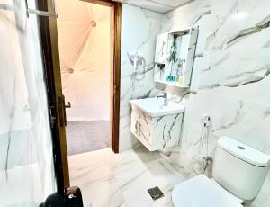 a white bathroom with a sink and a toilet at Shebara Camp Wadi Rum in Wadi Rum