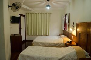 a hotel room with two beds and a window at Pousada dos Bandeirantes in Ouro Preto