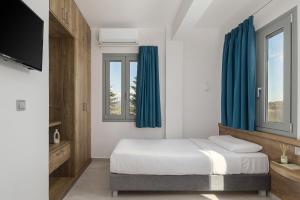 a bedroom with a bed with blue curtains and a tv at Areti Guesthouse in Víssani +36 photos