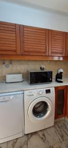 a kitchen with a washing machine and a microwave at Apartamento Neptuno in Benagil