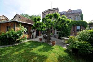 un patio trasero de una casa con un árbol en el patio en La Rosace, en Chartres