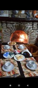 a table with plates of food on it with a fireplace at Hostal Periodista in Villa Carlos Paz