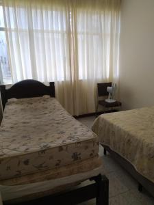 ein Schlafzimmer mit zwei Betten, einem Stuhl und einem Fenster in der Unterkunft Centro - Perto de tudo in Salvador