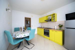 a kitchen with yellow cabinets and a table with blue chairs at Apartments by the sea Savar, Dugi otok - 23087 in Veli Rat