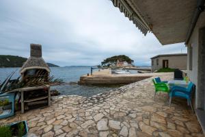 a patio with a table and chairs next to the water at Apartments by the sea Savar, Dugi otok - 23087 in Veli Rat