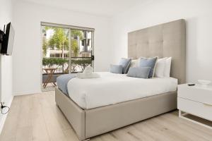 a white bedroom with a large bed and a window at Saltair Retreat in Gold Coast +28 photos