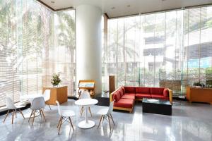 a living room with a red couch and white chairs at Riverine Place Hotel and Residence in Nonthaburi