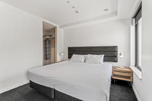 ein weißes Schlafzimmer mit einem großen Bett und einem Nachttisch in der Unterkunft Residence du Parc by Staysouth in Queenstown + 113 Fotos