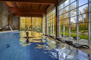 a woman in a hot tub in a room with windows at Hotel Zochova Chata - Adult friendly in Modra