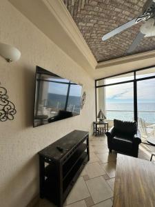 a living room with a tv and a couch and a chair at Palacio Del Mar - Oceanfront in Puerto Peñasco
