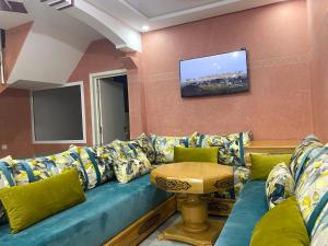 a living room with a blue couch and a tv at Cozy & Peaceful Getaway - Private Terrace in Tamraght Ou Fella