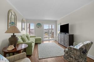 a living room with a green couch and a television at Summer School condo in Atlantic Beach