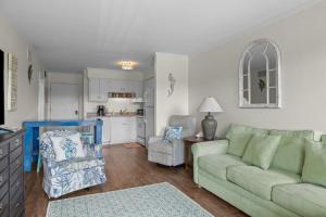 a living room with a green couch and a kitchen at Summer School condo in Atlantic Beach