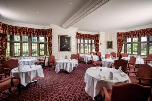 a restaurant with white tables and chairs and windows at Buckland Manor - A Relais & Chateaux Hotel in Broadway