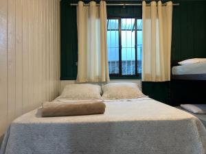a bed with a pillow on it in a bedroom at CASA SUZENA - Penha SC a 300 metros do Beto Carrero e Praias in Penha