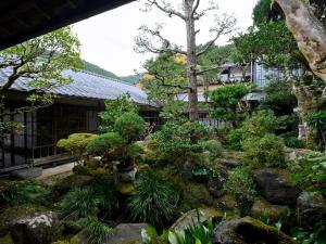 a garden of trees and plants in front of a building at Ryouriryokan Asahikan in Shionoha