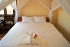 a bedroom with a white bed with a flower on it at Gold Sand Beach Bungalow in Phu Quoc