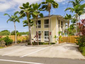 a yellow house with palm trees in the driveway at Kona Wave Rider - Island Sanctuary with Ocean Soul in Kailua-Kona