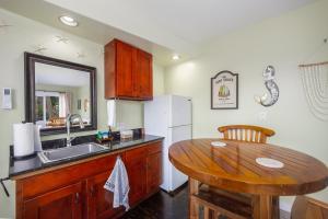 a kitchen with a wooden table and a sink at Kona Wave Rider - Island Sanctuary with Ocean Soul in Kailua-Kona +6 photos