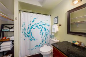 a bathroom with a shower curtain with blue fish on it at Kona Wave Rider - Island Sanctuary with Ocean Soul in Kailua-Kona